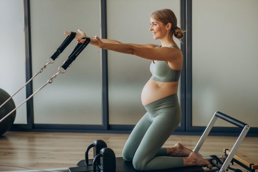 pregnant-woman-exercising-with-help-reformer-pilates-class-scaled.jpg