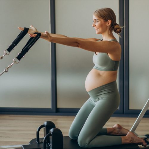 pregnant-woman-exercising-with-help-reformer-pilates-class-scaled.jpg